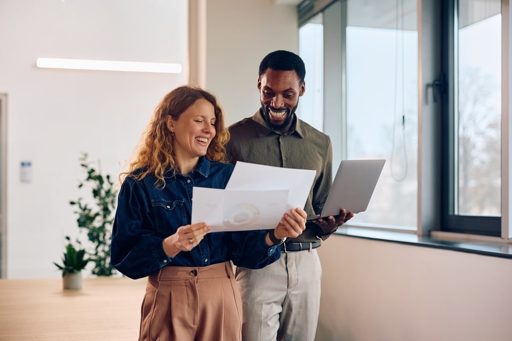 Happy,Businesswoman,And,Her,African,American,Coworker,Working,On,Reports